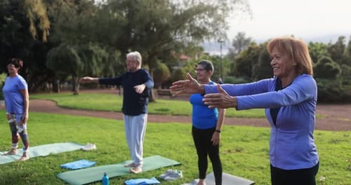 Senior people doing yoga exercises outdoor with city park in background - Healthy lifestyle