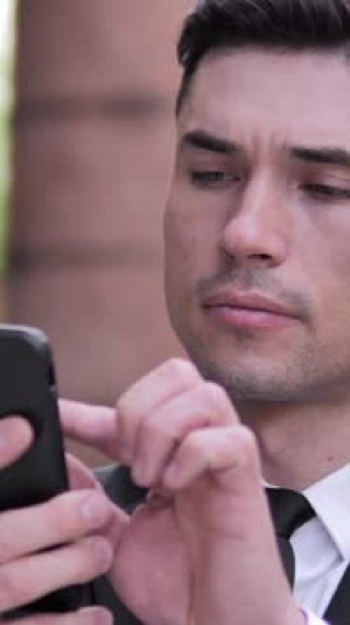 Focused Man Uses Smartphone in Urban Setting