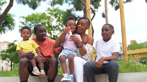 African black ethnic family with children in playground blowing soap bubbles