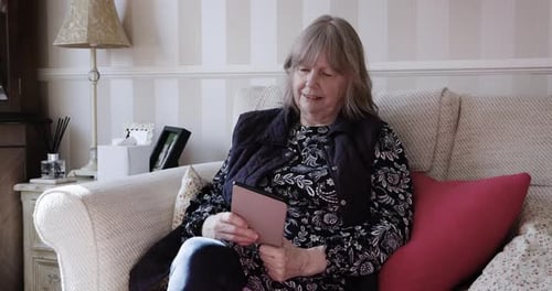 Mature Woman Reading on Tablet at Home