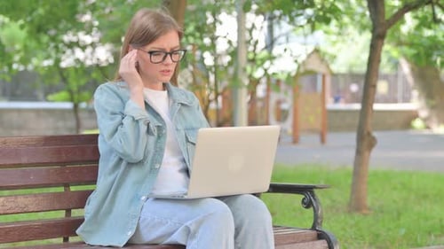 Stressed Young Woman with Laptop on Park Bench