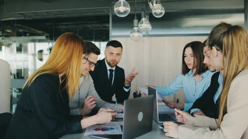 In a Modern Office a Group of Business Professionals Collaborates on a Project Discussing Ideas and