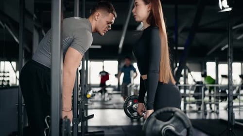 Fitness Trainer Guides Woman in Deadlifts Building Strength and Trust in the Gym