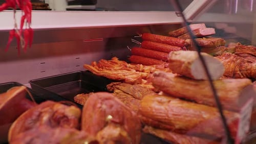 Butchers hands placing smoked loin pieces in a shop window for sale.