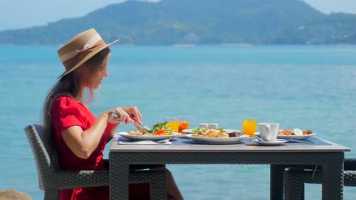 A Young Woman on Vacation Delights in Her Breakfast at a Luxury Resort