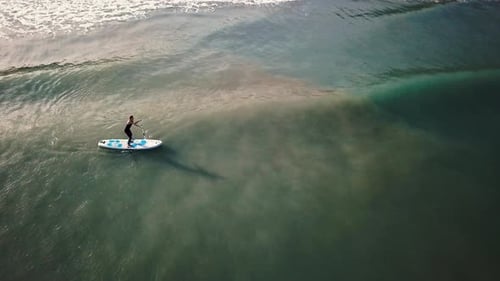 Female practice paddle boarding in the sea, view from drone