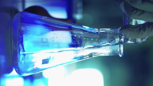 Scientist in Laboratory Doing Chemical Experiment with Liquid in Tube and Flasks