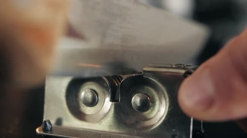 Man Sharpening the Knife with a Whetstone on a Wooden Background Close Up