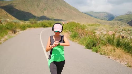 A Brunette Warms Up Starting Her Fitness Tracker and Shifting Into a Run