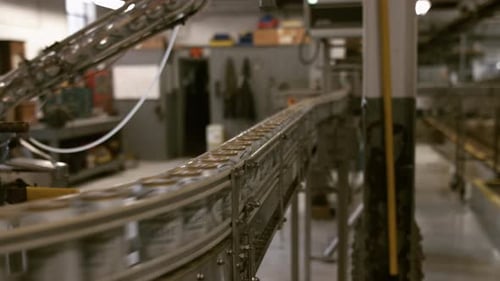 Cans traveling on conveyor line in manufacturing and bottling plant, dolly slider shot