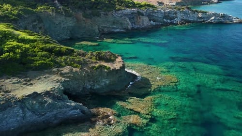 A rocky coastline meets crystal clear turquoise waters in a stunning aerial view
