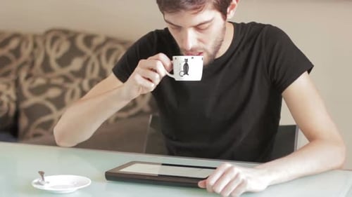 Male college student using tablet computer and having coffee