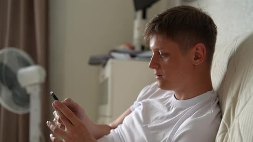 Man Relaxing at Home Using Smartphone