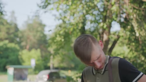 Anxious Youth Outdoors Youth Checks Bag In Park Young Man Surveys Surroundings Cautiously Outdoors
