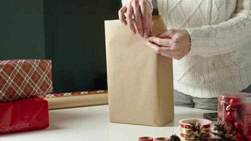 Woman Closing a Christmas Gift Bag at Home