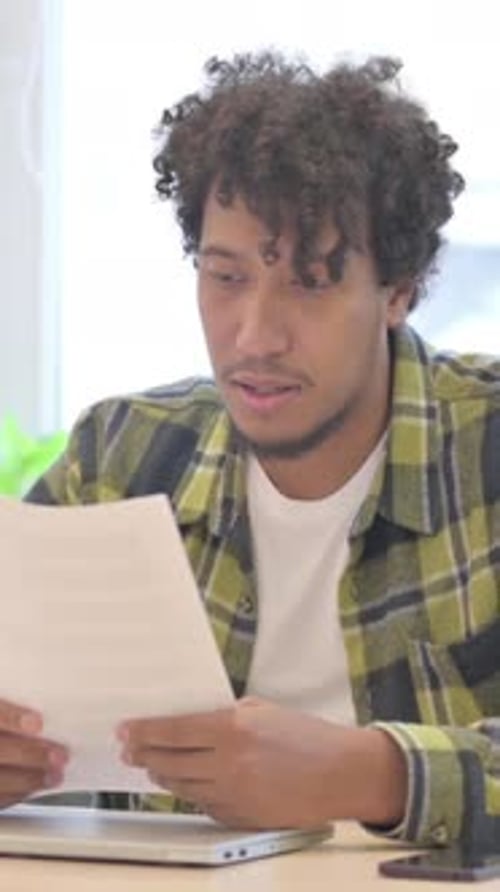 Young Man Reviews Documents at Table Indoors