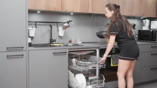 Woman Unloads Dishwasher in Modern Home Kitchen