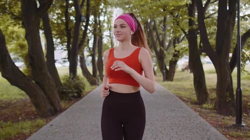 Athletic Fitness Sport Runner Girl Training Marathon Run Listening Music in Earphones Oudoors Park