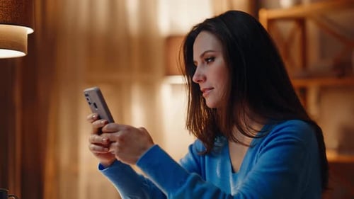 Entspannte Hausfrau beim Surfen auf dem Smartphone, sitzt am Abend, Wohnung, Nahaufnahme