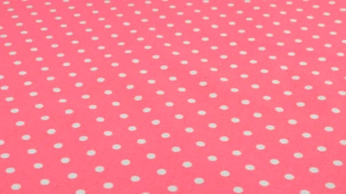 Close-up view of the taffy pink with white polka dots cotton fabric rotated on the display case.