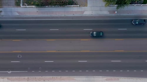 Automobile vehicles driving on city road, aerial bird's eye view, slow motion