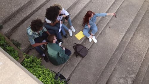 multiracial students sitting on stairs of university campus, high angle shot