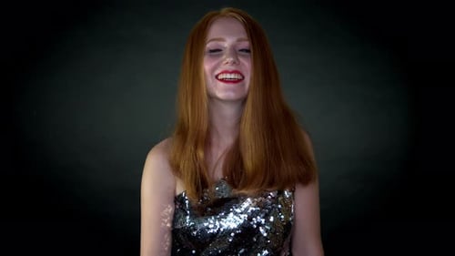 A young beautiful woman in shimmery dress ,all happy and joyous, laughing and smiling looking toward