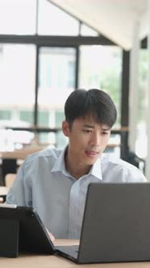 Young Adult Working on Laptop and Tablet Indoors