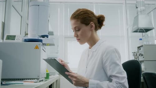 Woman Scientist Writes on Clipboard in Modern Laboratory