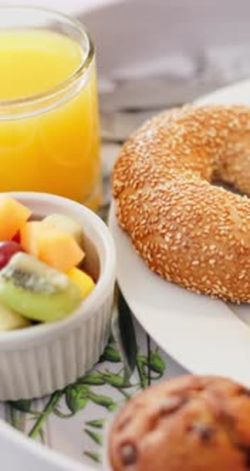 Delicious breakfast featuring bagel, fruit, juice, and muffin