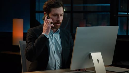 Caucasian Man Sit at Desk Evening Night Office Work Online on Computer Answer Mobile Call Adult