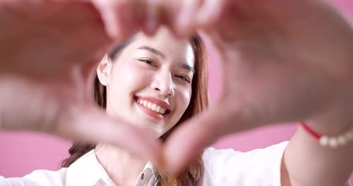 Smiling Woman Makes Heart Shape with Hands