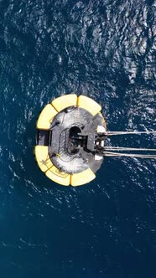Top down aerial of yellow and black buoy with ropes tied to it