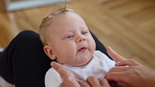 Parents play with their adorable baby. Dad’s fingers touch cute plump kid’s cheeks. Close up.