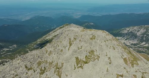 Rocky mountain tall peak surrounded by mountain ranges, on a clear sunny day with blue skies and vib