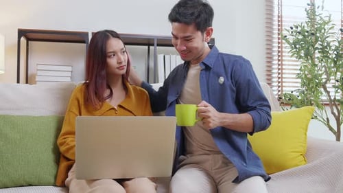 Young Couple Using Laptop at Home on Sofa