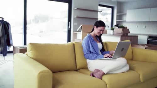 Woman Using Laptop on Couch in New Home
