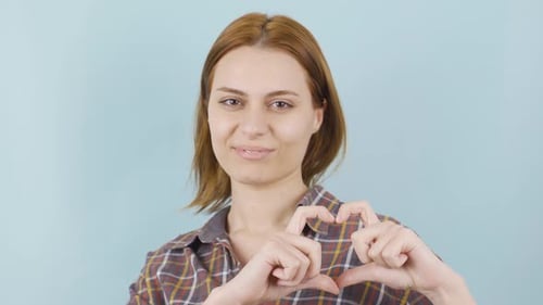 Woman Smiling and Making Heart Shape with Hands