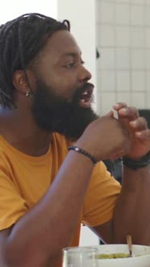 Vertical video: Man replying leaning gesturing, dining bowl animated cues fading as listening right