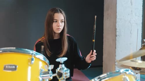 A Teenage Girl Plays the Drums in the Studio Beating the Rhythm with Sticks