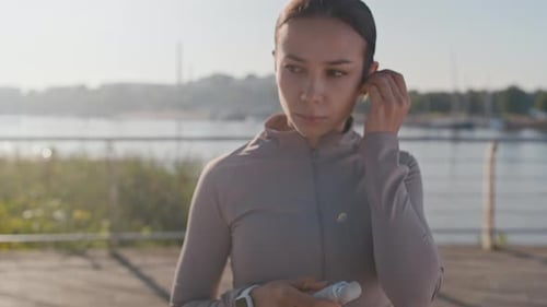 Athletic Woman Puts Wireless Earbud In Before Running