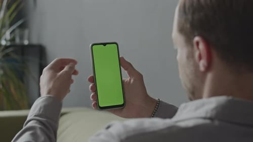 Man Looking at Mobile Phone with Green Screen in Office