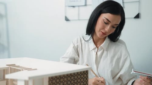 Woman Reviews Model of Modern Building with Ruler