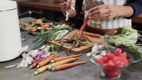 Woman Peeling Carrot with Tool in Kitchen