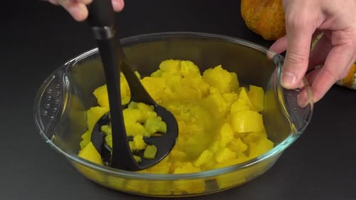Mashing Cooked Orange Squash in Glass Bowl
