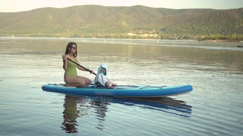 Woman and Child Paddleboarding on a Calm Lake