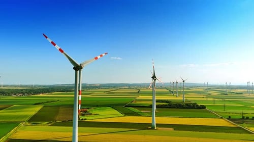 Green agricultural plantations with multiple wind turbines. Clean energy production. Aerial view.