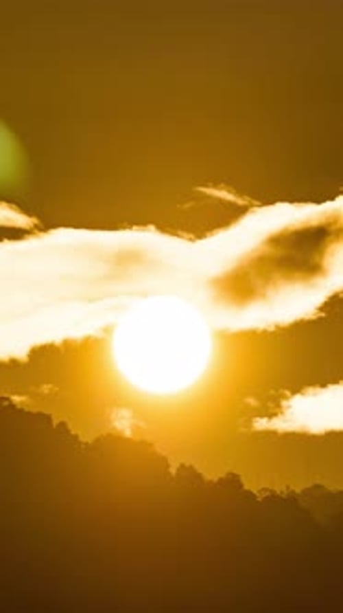 Golden Sun Shining Behind Clouds Over Silhouetted Hills