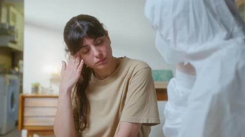Female Patient Having Talk with Doctor in Coverall at Home