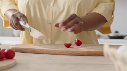 Adult Cuts Cherry Tomatoes on a Cutting Board